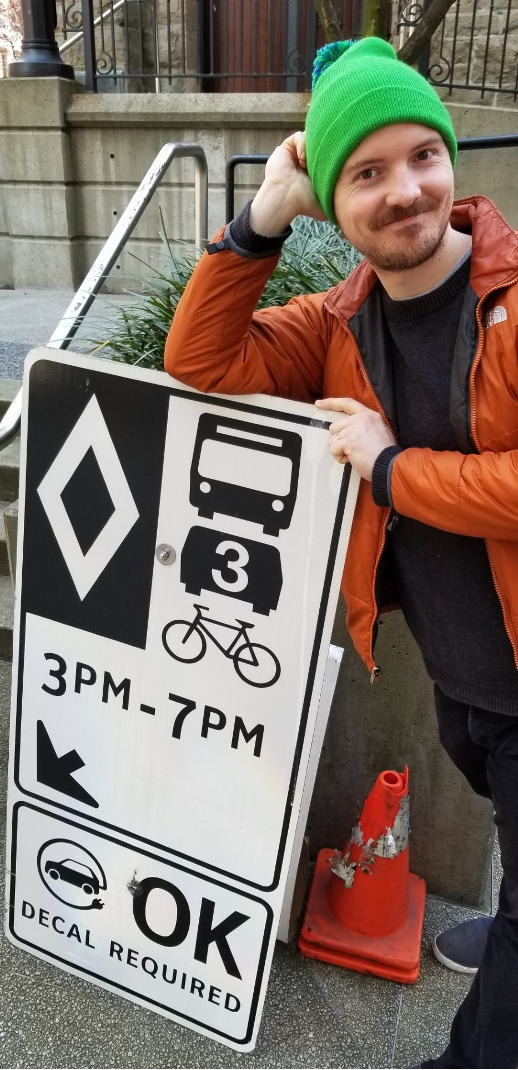 Denis Agar beside a transit and cycling street sign